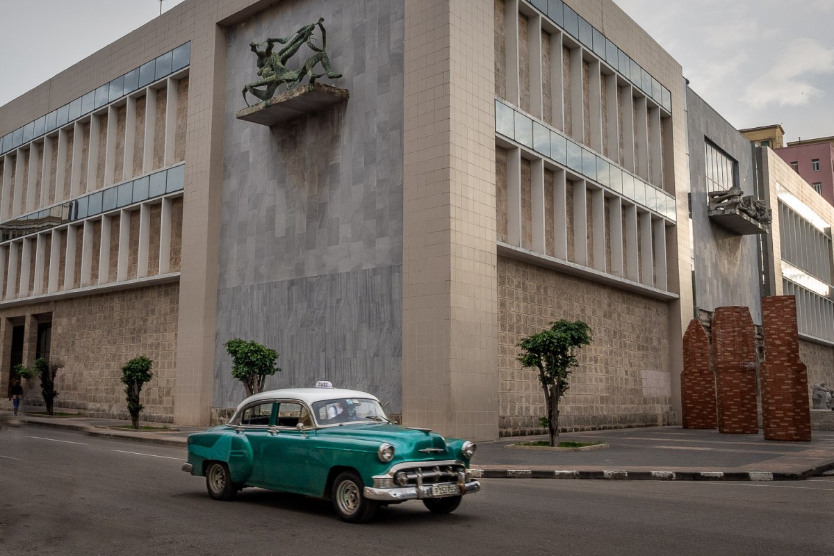 Car passing a public building, Havana, Cuba.