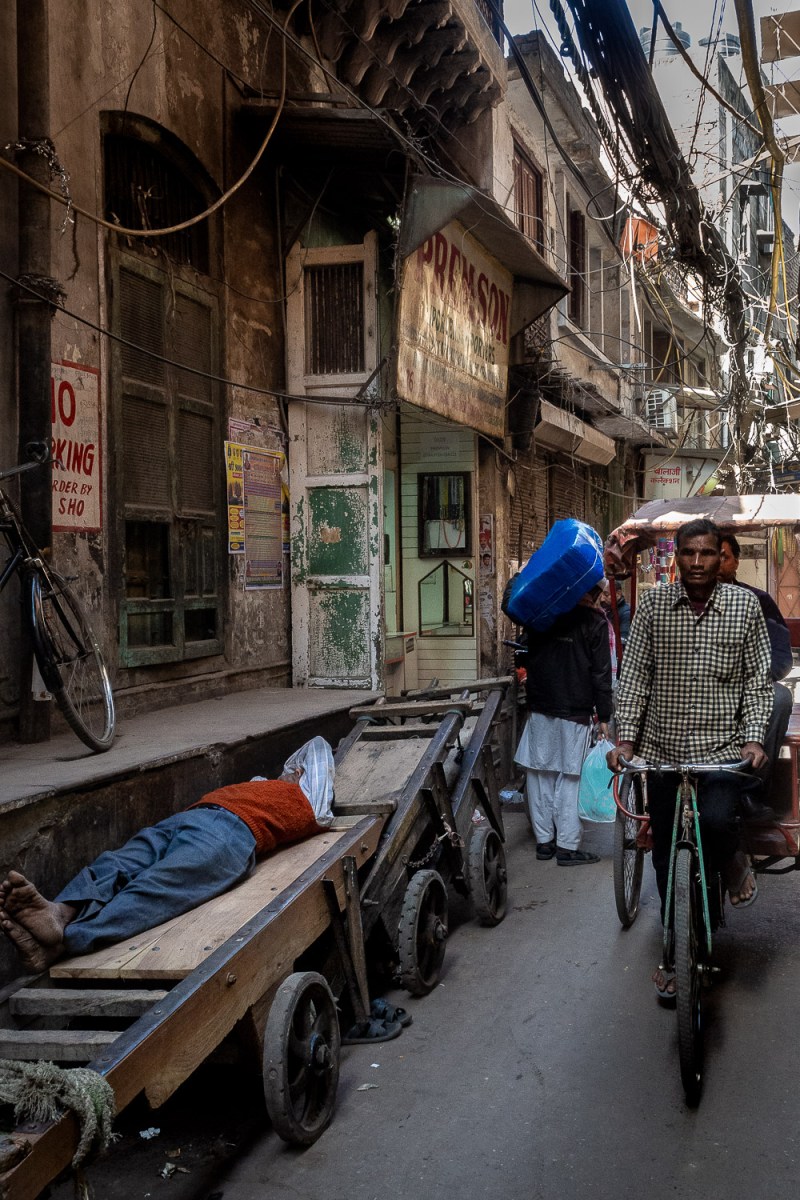 Man sleeping on a wheelbarrow, Old Delhi, India.