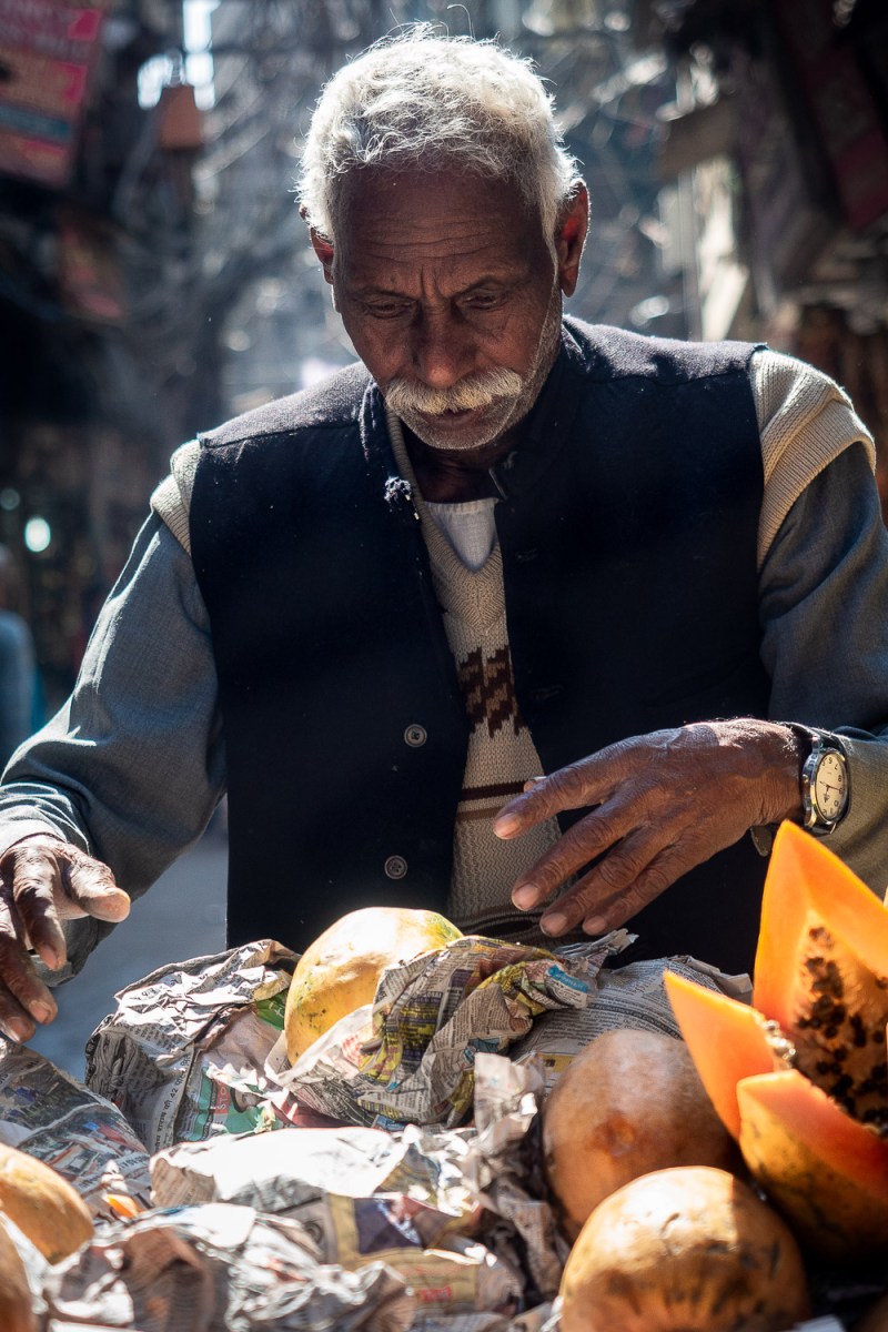 Man selling papayas wraped in newspaper, Old Delhi, India.