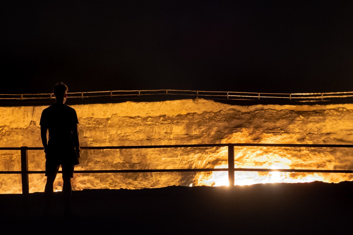 Man standing at the Darvaza gas crater, Karakum Desert, Turkmenistan.